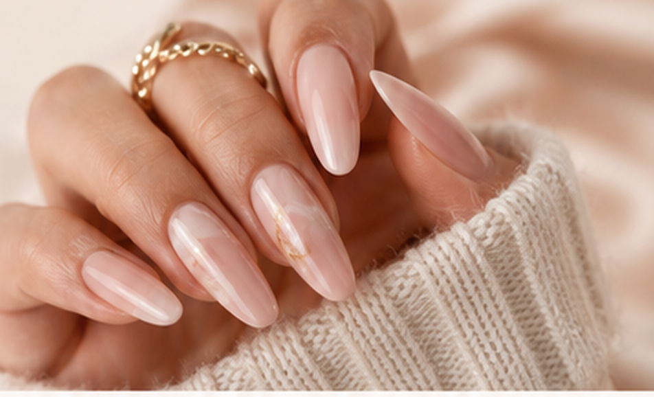 Hand with glossy nude almond press-on nails resting on cream knit sweater